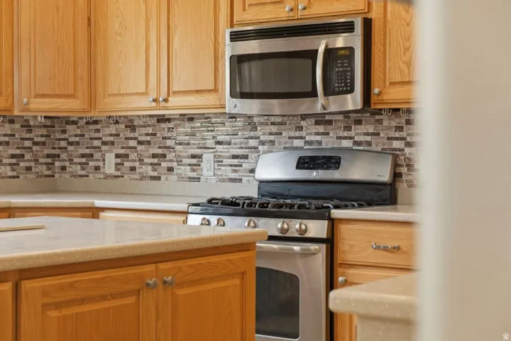 Kitchen with stainless steel appliances, light countertops, and decorative backsplash