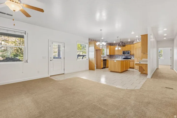 Kitchen featuring light colored carpet, a kitchen island, light tile patterned floors, and hanging lights