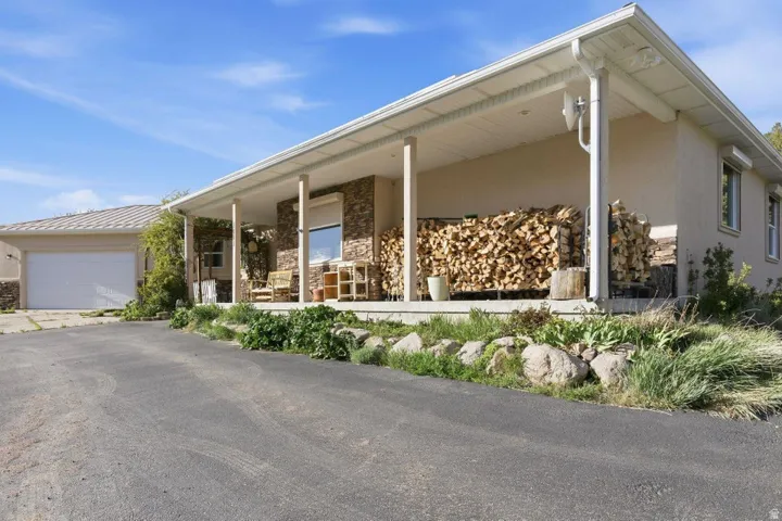 View of front facade with stone siding, stucco siding, covered porch, and a garage
