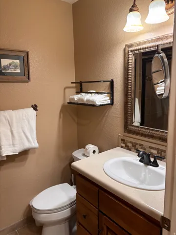 Half bath featuring a textured wall, vanity, and decorative backsplash