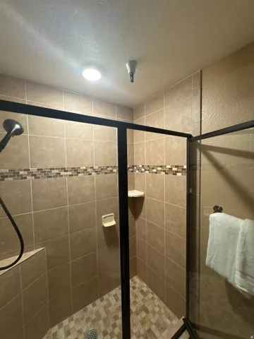 Bathroom featuring a textured ceiling, a shower stall, and a textured wall