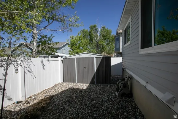 Fenced backyard featuring a shed