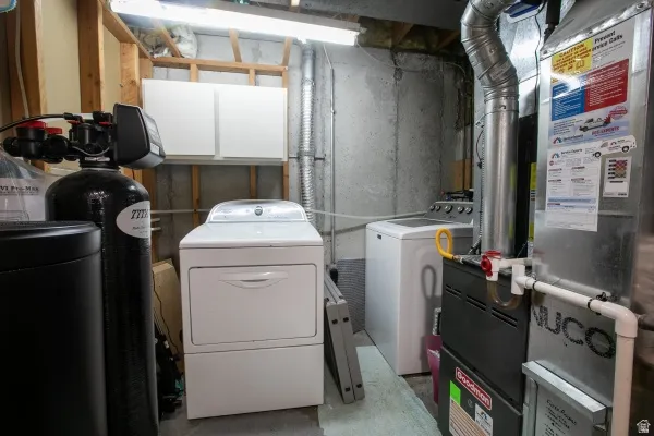 Laundry room with heating unit, separate washer and dryer, and concrete flooring
