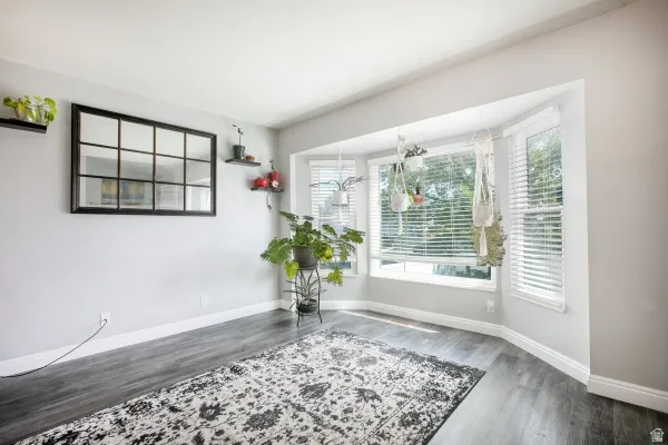 Unfurnished dining area featuring dark wood-type flooring and baseboards