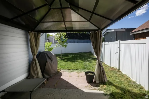 Fenced backyard featuring a patio area, a grill, and a gazebo