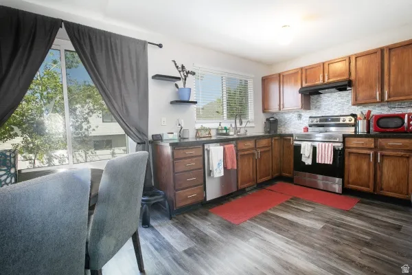 Kitchen with stainless steel appliances, dark wood-style flooring, tasteful backsplash, wood finish cabinetry, and open shelves