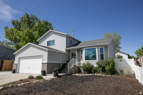 Tri-level home with brick siding, an attached garage, and concrete driveway
