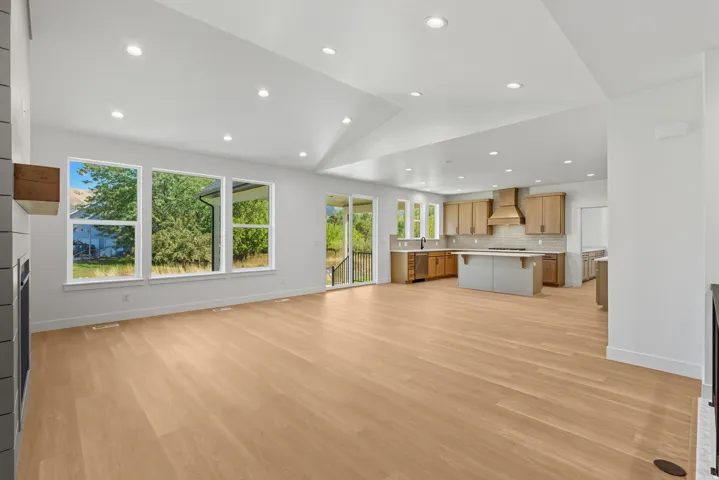 Unfurnished living room with a glass covered fireplace, light wood-type flooring, recessed lighting, and vaulted ceiling