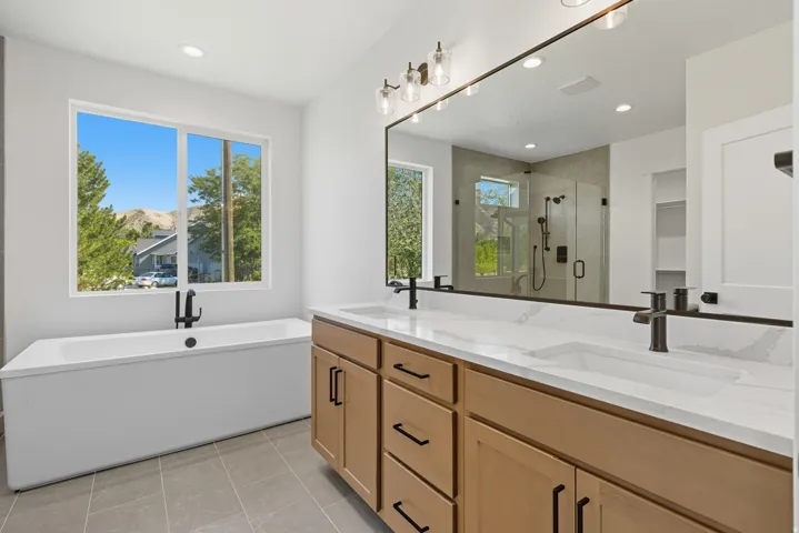 Full bathroom featuring a freestanding bath, a shower stall, double vanity, light tile patterned floors, and recessed lighting
