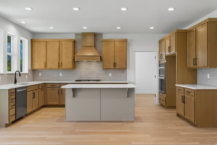 Kitchen with backsplash, wood finish cabinetry, a kitchen bar, light wood finished floors, and recessed lighting