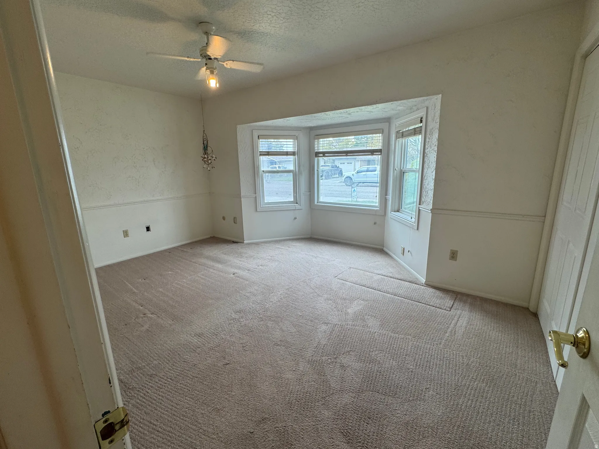 Unfurnished bedroom featuring light carpet, a textured ceiling, ceiling fan, and a textured wall