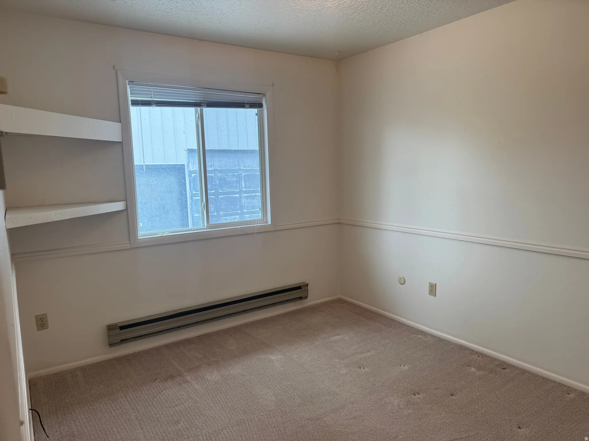 Spare room with baseboard heating, light colored carpet, and a textured ceiling