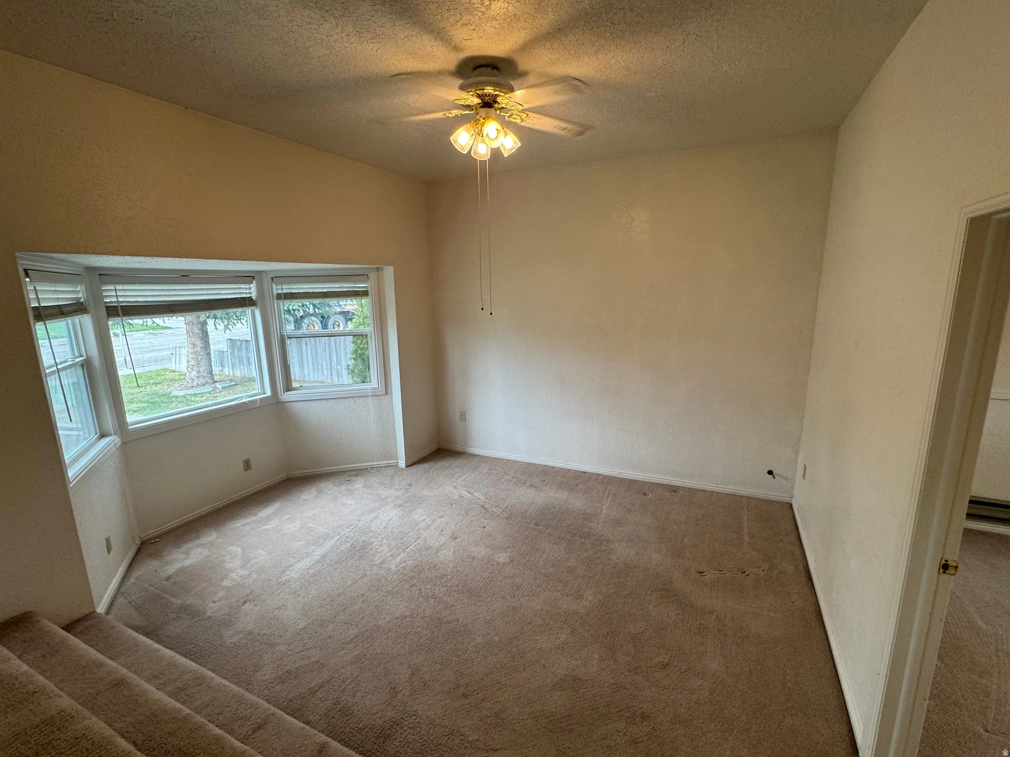 Carpeted spare room with a textured ceiling and ceiling fan