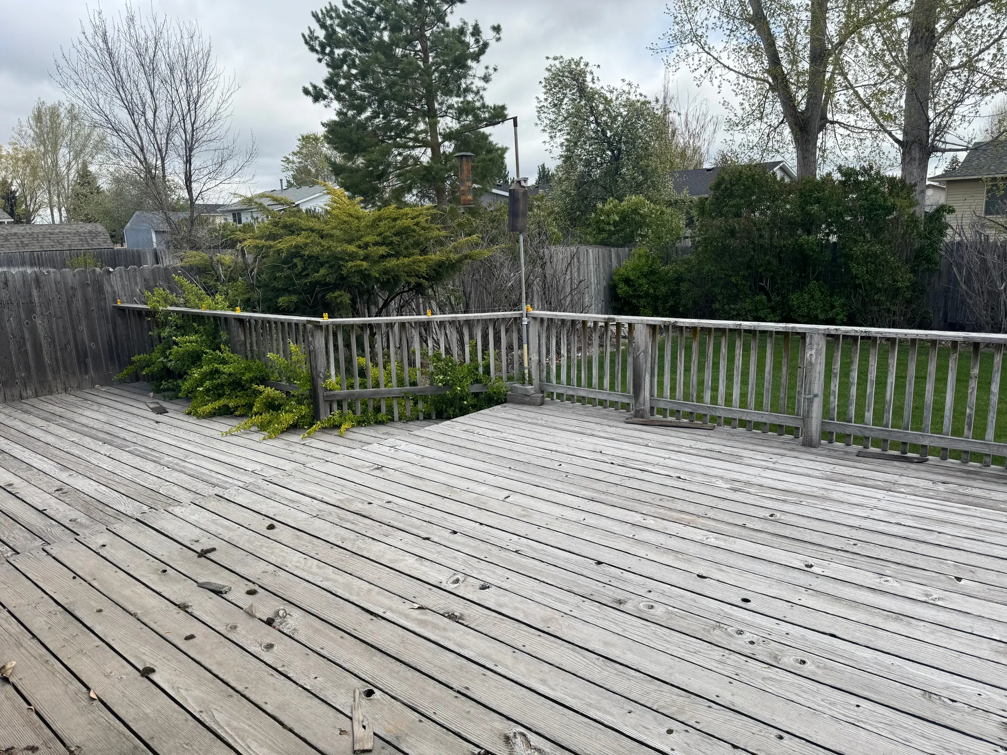 Wooden terrace with a fenced backyard