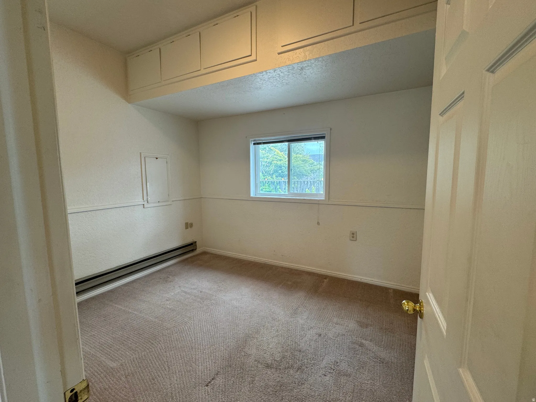 Unfurnished room featuring carpet flooring and a baseboard heating unit