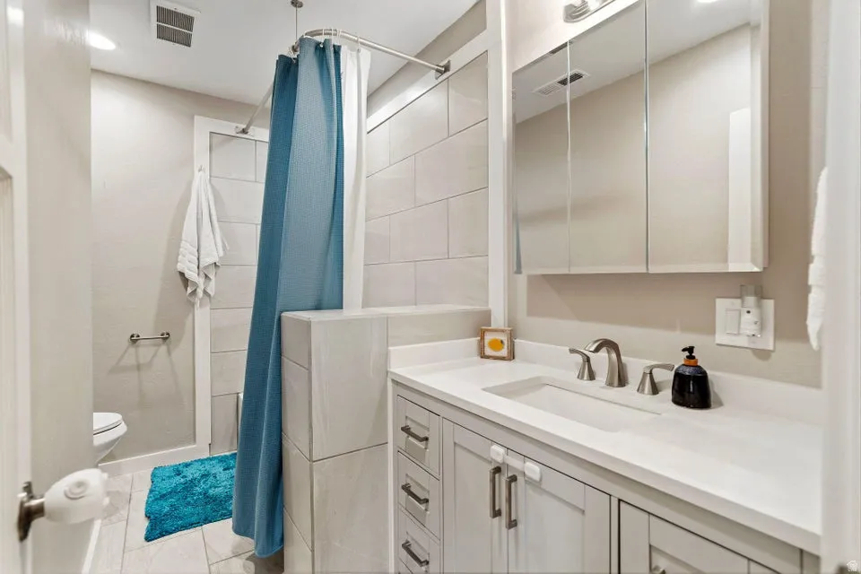 Full bathroom with a stall shower, vanity, and light tile patterned floors
