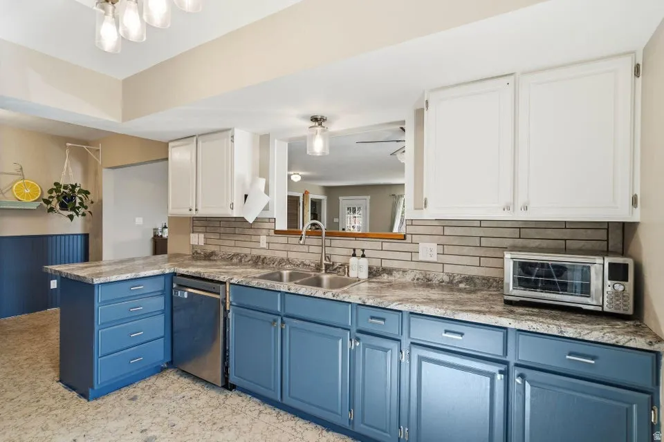 Dual tone kitchen with two tone cabinets, light countertops, decorative backsplash, a peninsula, and dishwasher