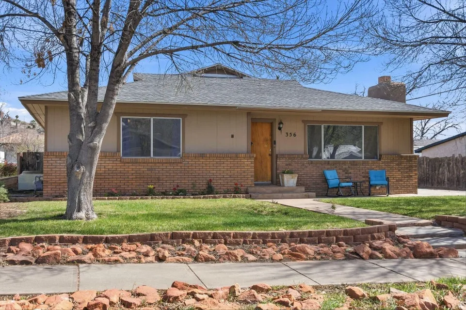 Bungalow with brick siding, a chimney, and roof with shingles