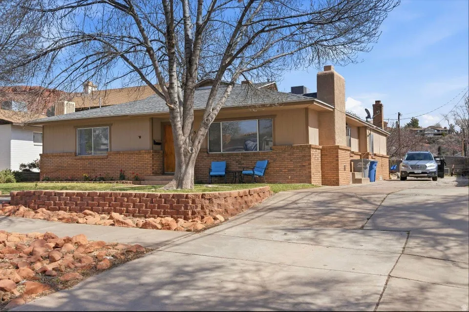 View of front of house with brick siding, a chimney, and driveway