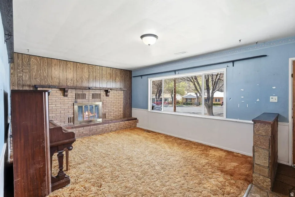 Unfurnished living room featuring a fireplace, carpet floors, and wooden walls