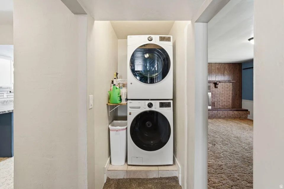 Laundry area with light colored carpet and stacked washer and clothes dryer