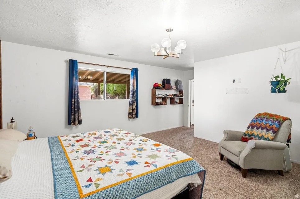 Bedroom with carpet flooring, hanging lights, and a textured ceiling