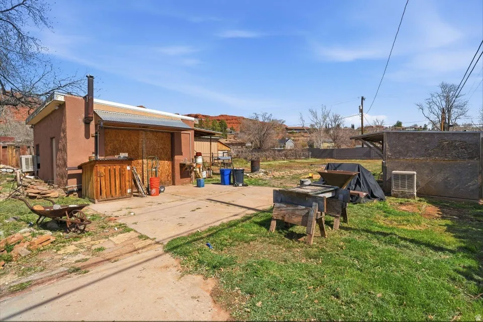 View of green lawn with a patio area and an outbuilding
