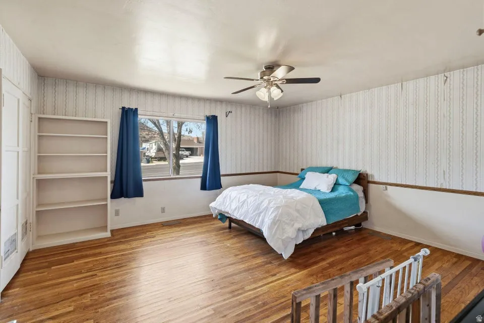 Bedroom featuring wallpapered walls, wood-type flooring, and ceiling fan