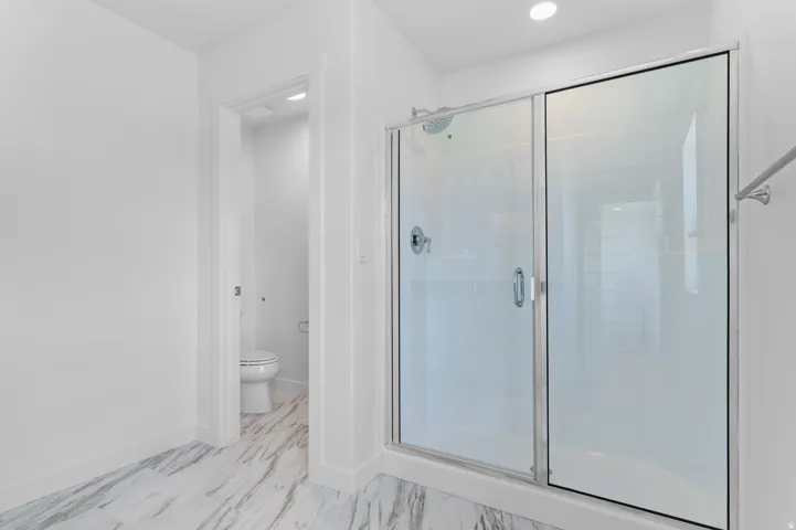 Spacious shower enclosure with clear glass doors and chrome hardware