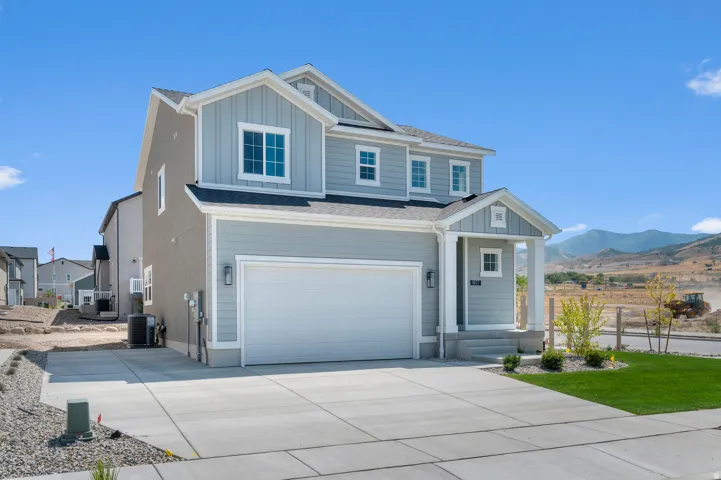 Two-story residence featuring a two-car garage, covered porch, and light blue siding