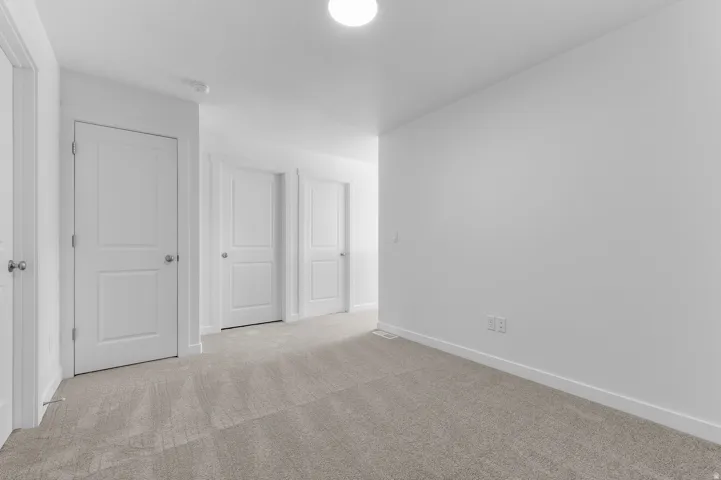 Neutral tone carpeting, white walls, and bright overhead lighting define this interior space