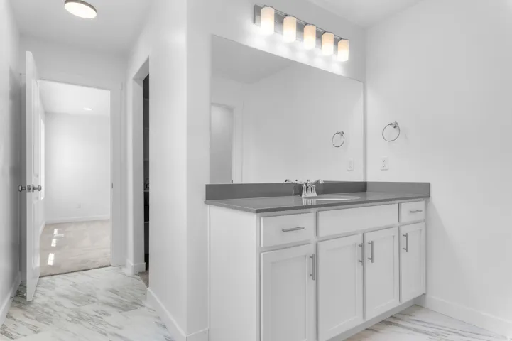 Bathroom vanity featuring a single sink with chrome faucet, a large mirror, and a five-light fixture