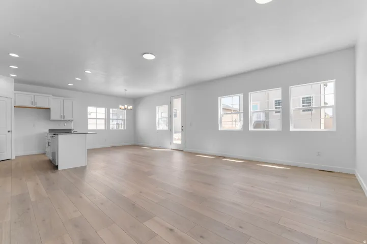 Spacious living area featuring light wood-finish flooring and abundant natural light from multiple windows