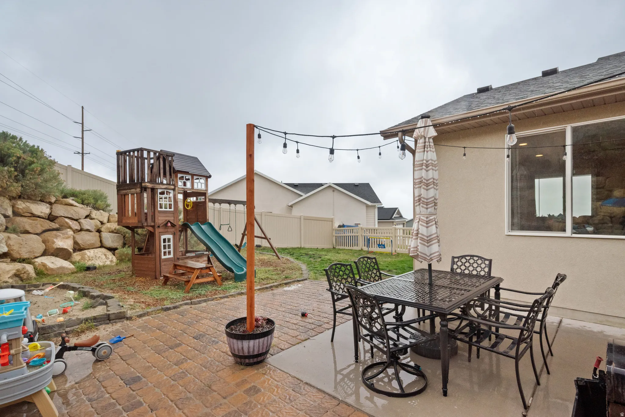 Fenced backyard with a patio area, outdoor dining space, and a playground