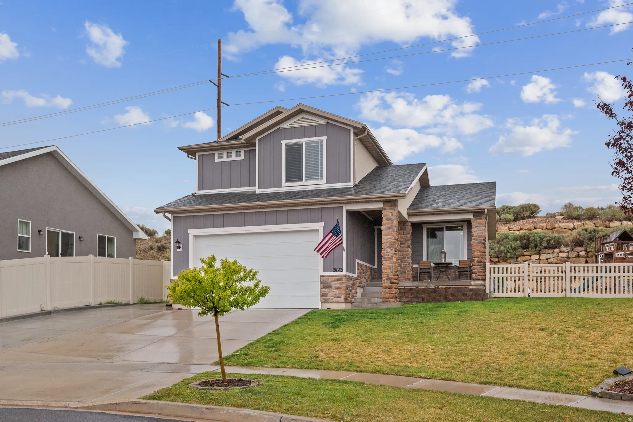 Craftsman-style home featuring a porch, a garage, board and batten siding, driveway, and stone siding