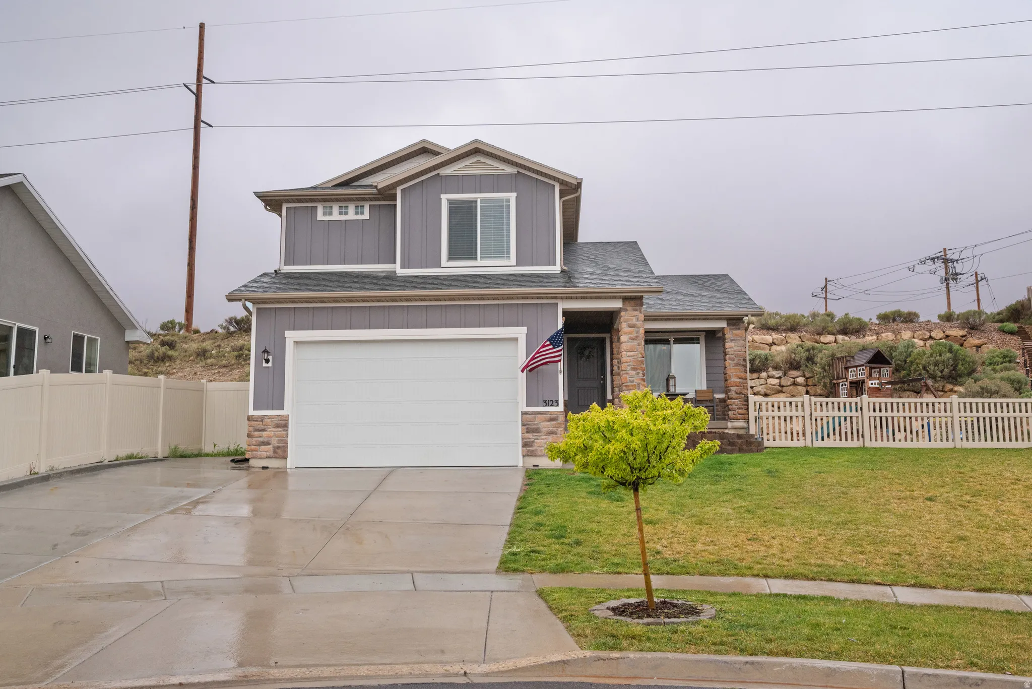 Craftsman inspired home featuring stone siding, an attached garage, driveway, board and batten siding, and a shingled roof