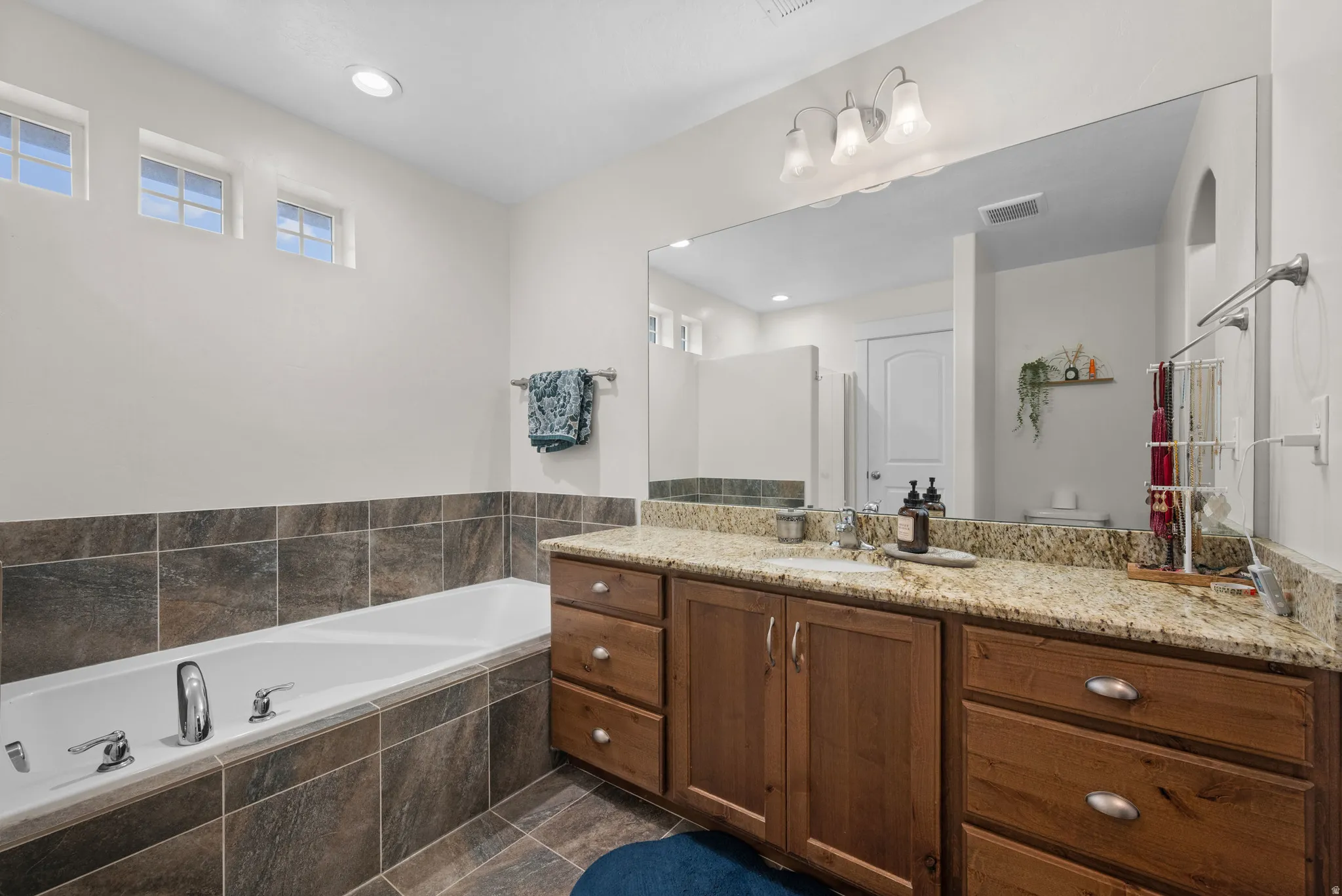 Bathroom with a bath, vanity, and recessed lighting