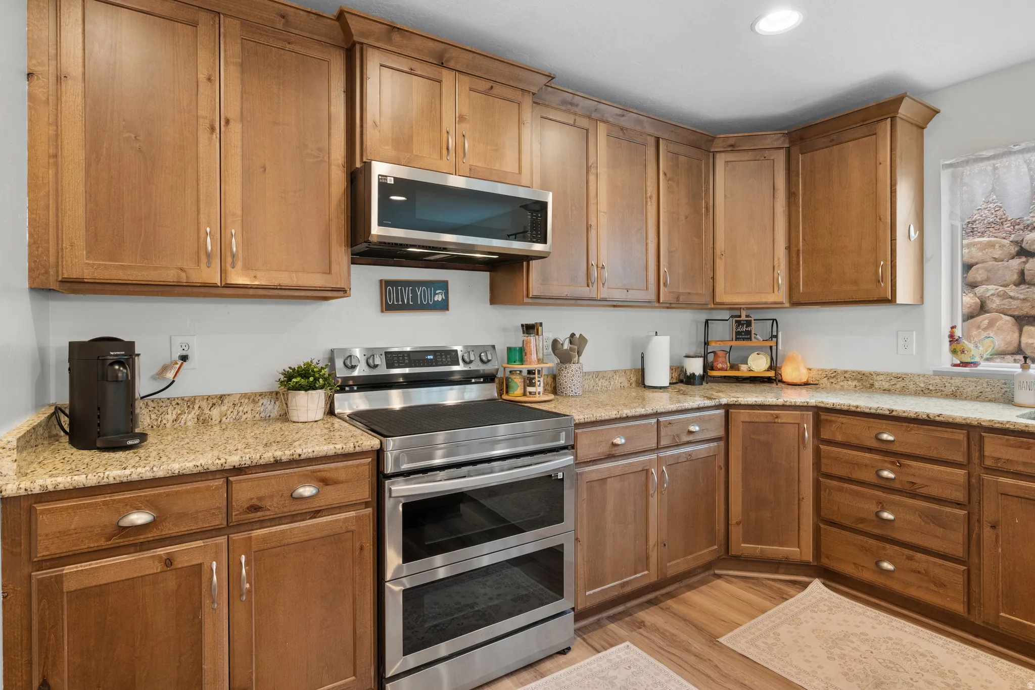 Kitchen with stainless steel appliances, light stone countertops, light wood finished floors, wood finish cabinetry, and recessed lighting