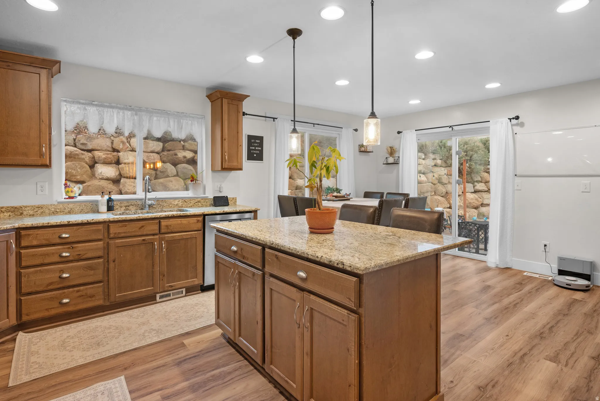 Kitchen featuring a center island, light wood finished floors, wood finish cabinetry, and light stone countertops