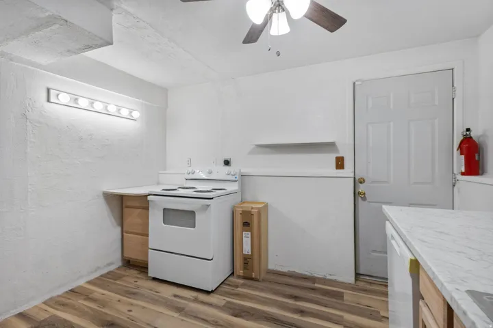 Kitchen area featuring wood-finish flooring, white appliances, and a ceiling fan