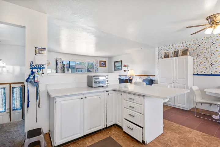 Kitchen area featuring white cabinetry, light-toned countertops, and an integrated breakfast bar