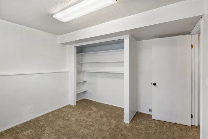 Room featuring built-in shelving, white walls, textured ceiling, and carpeting