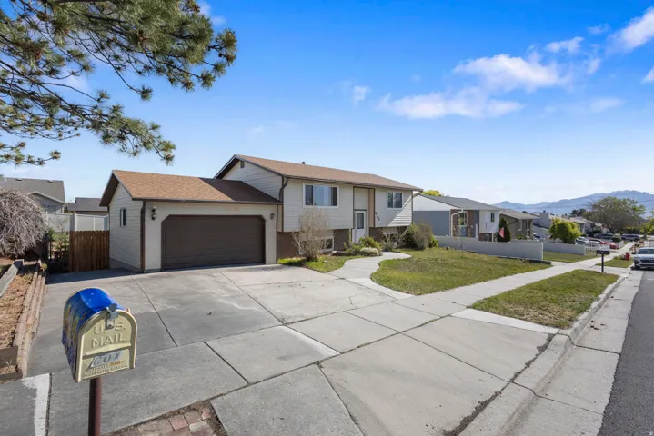 Split-level residence featuring a two-car attached garage, concrete driveway, and front lawn
