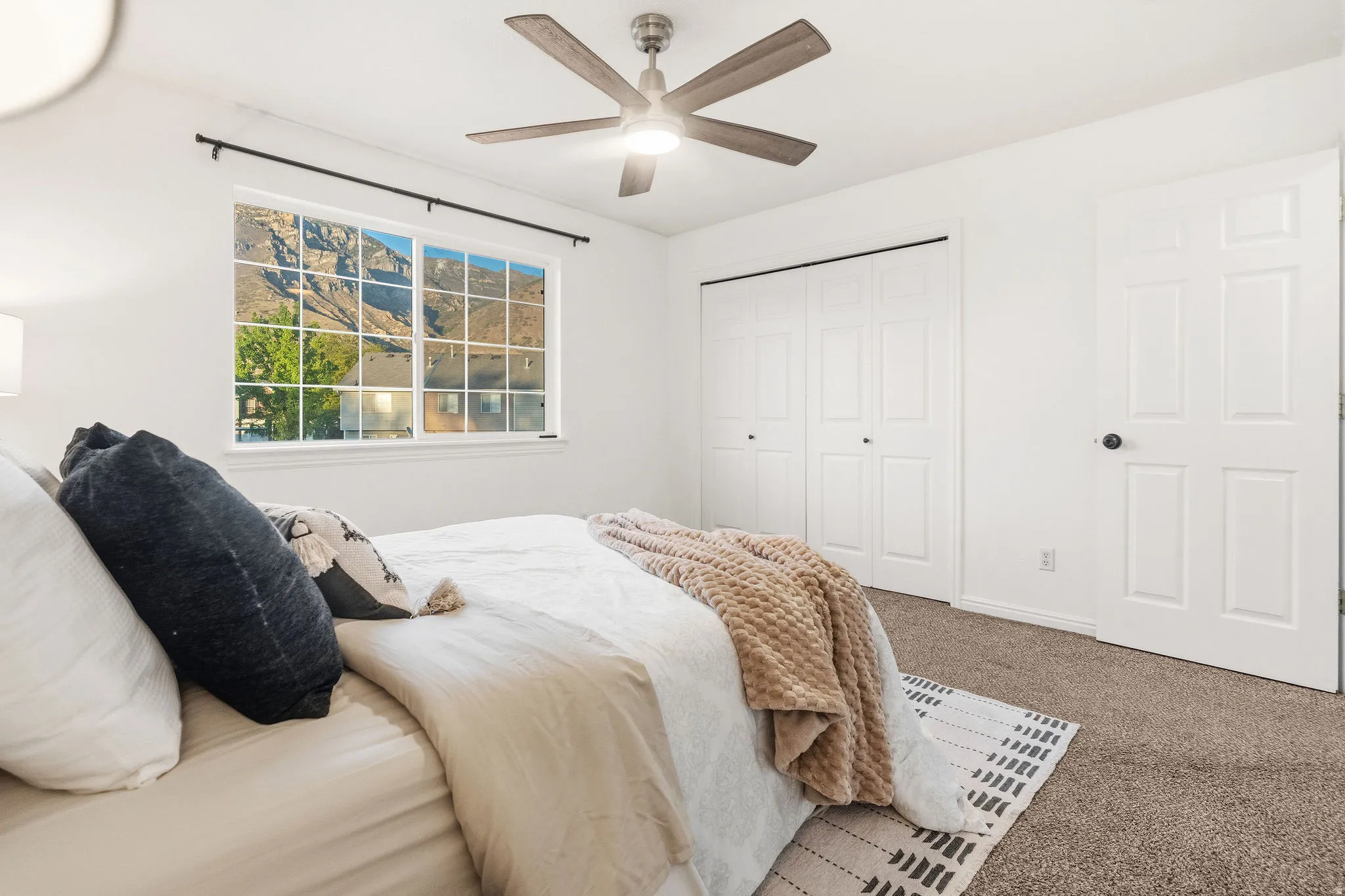 Carpeted bedroom with ceiling fan and a closet
