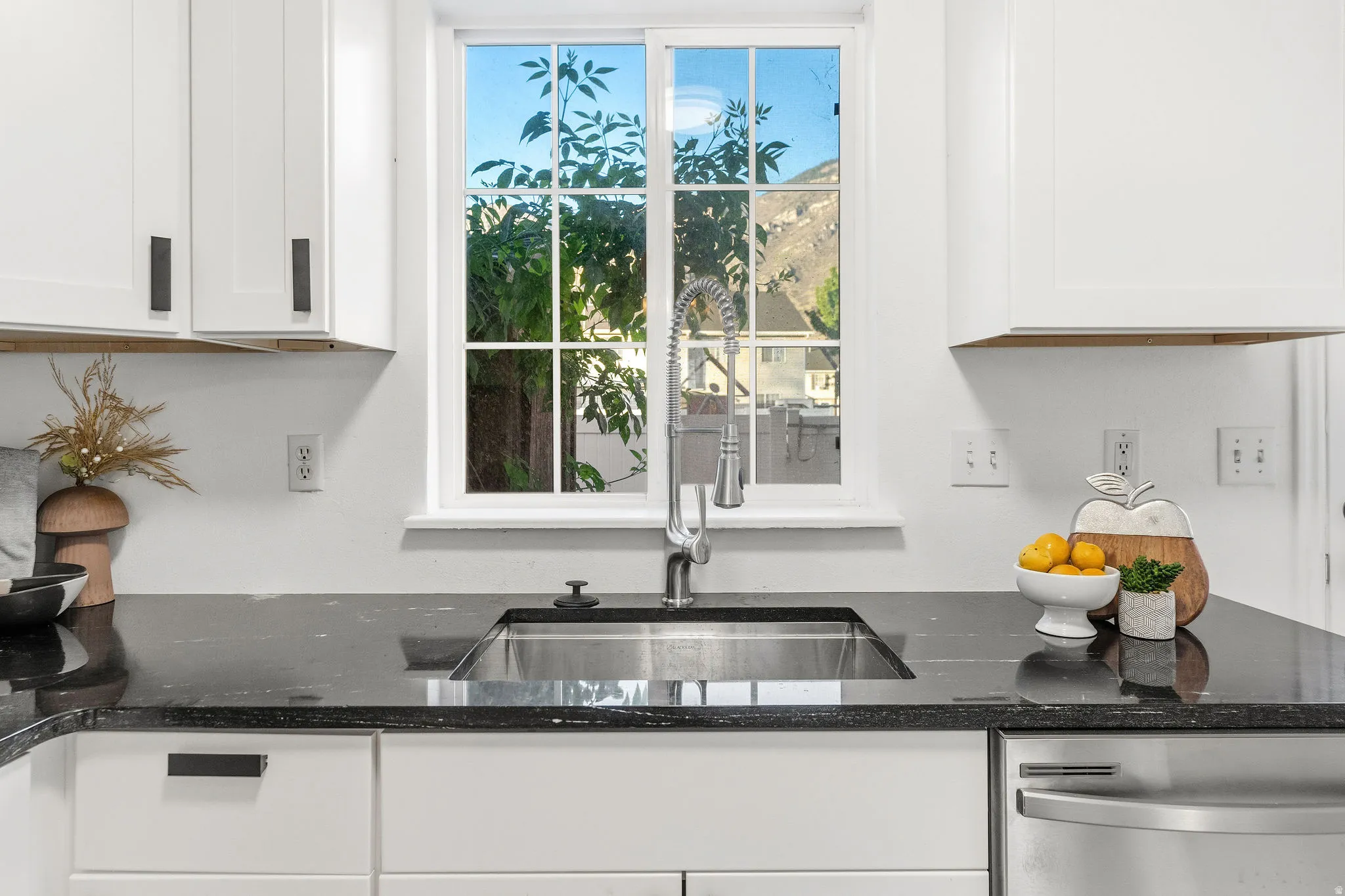 Kitchen with dark stone counters, white cabinets, and dishwasher