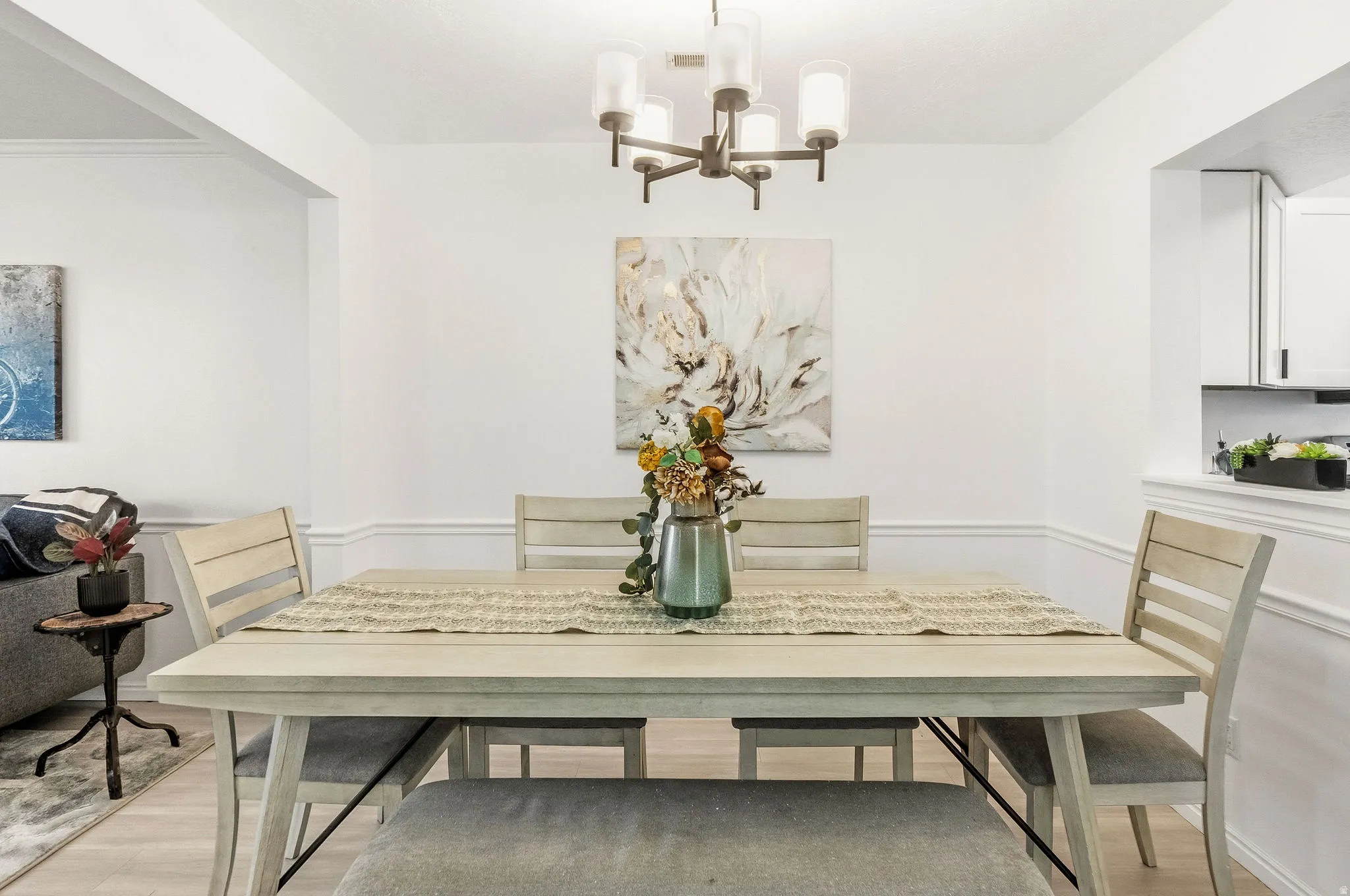 Dining room with suspended lighting, light wood-type flooring, and wainscoting