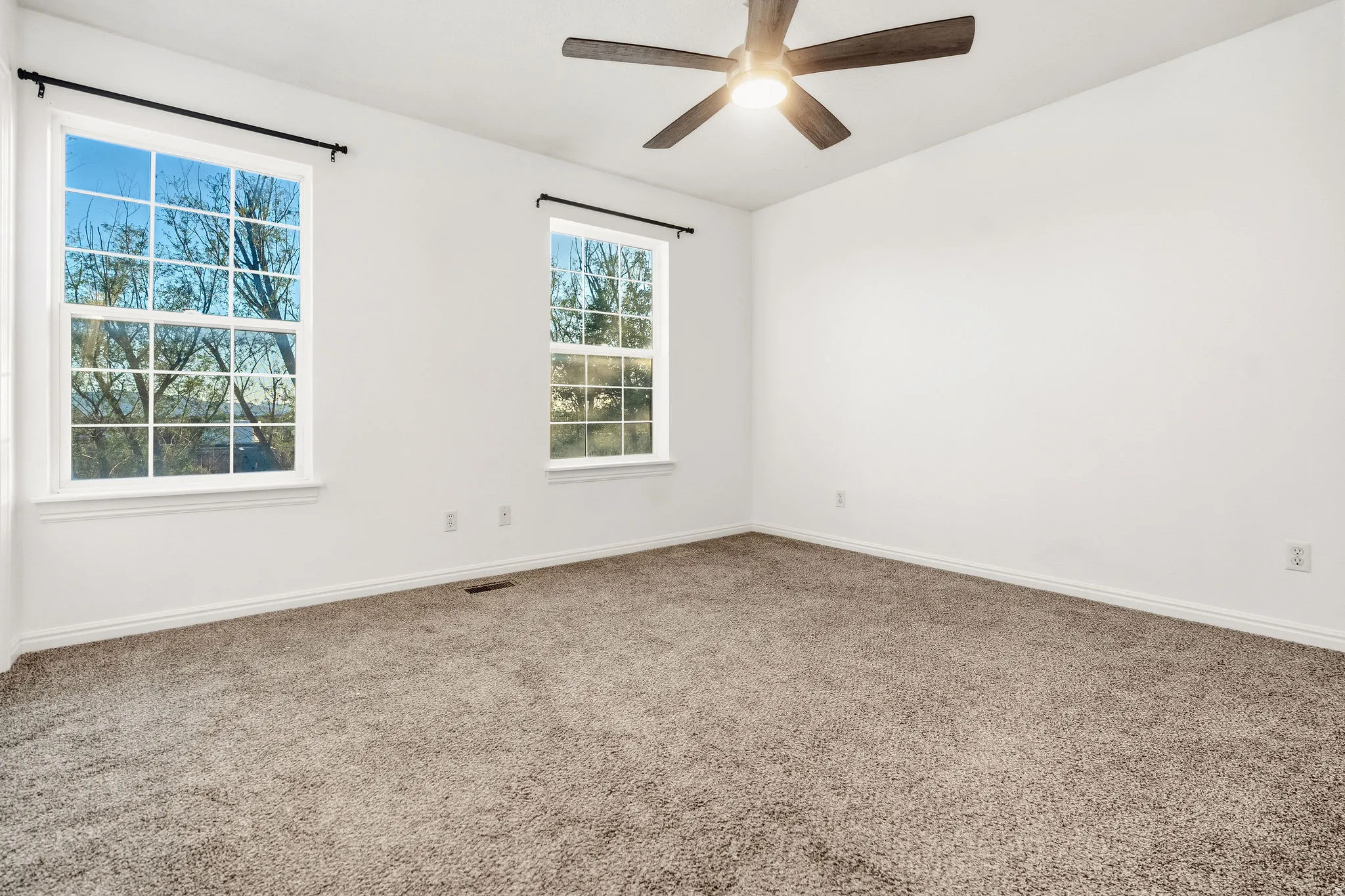 Empty room featuring carpet floors and a ceiling fan