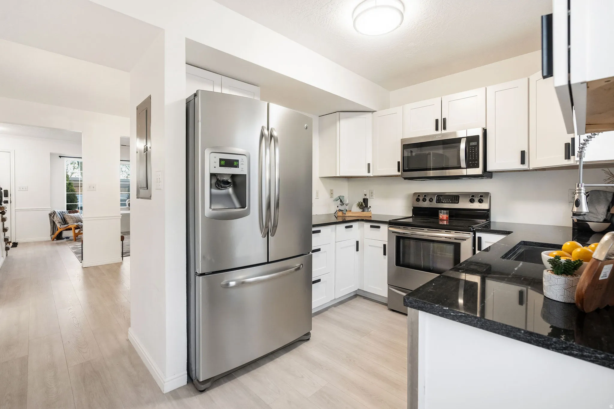 Kitchen with stainless steel appliances, light wood-style flooring, and white cabinets