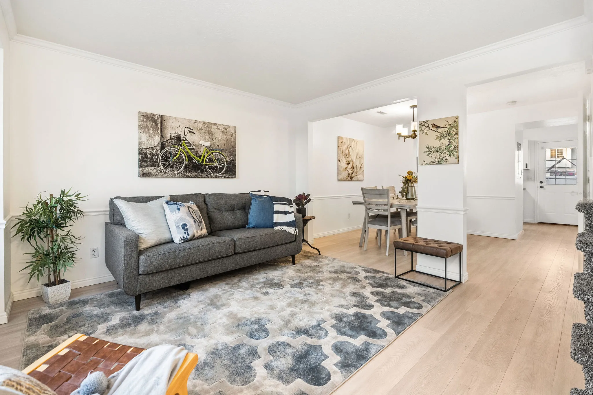 Living area with light wood-style floors, ornamental molding, and suspended lighting