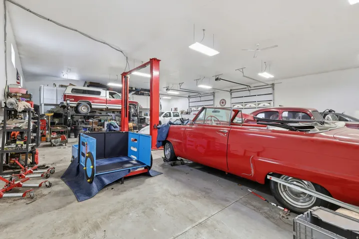 Spacious garage with multiple overhead doors, concrete flooring, and ample overhead lighting